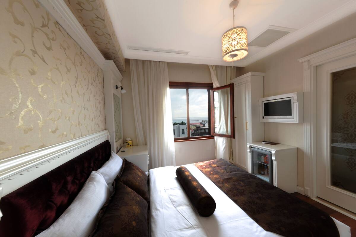 Una habitación de hotel con una cama grande, televisión y ventana con vistas.