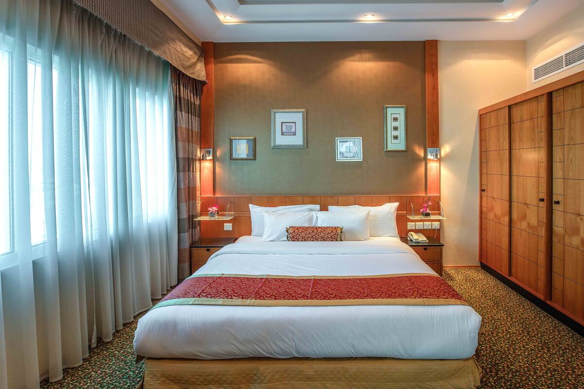 Una camera d'albergo con un letto grande, un armadio in legno e quadri appesi al muro.