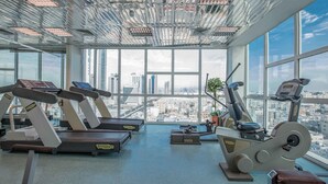 A gym with treadmills and exercise bikes, large windows, and a city view. - Gulf Court Hotel (Manama)