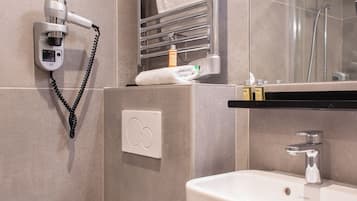 Uma casa de banho moderna com sanita, lavatório, porta-toalhas e secador de cabelo.