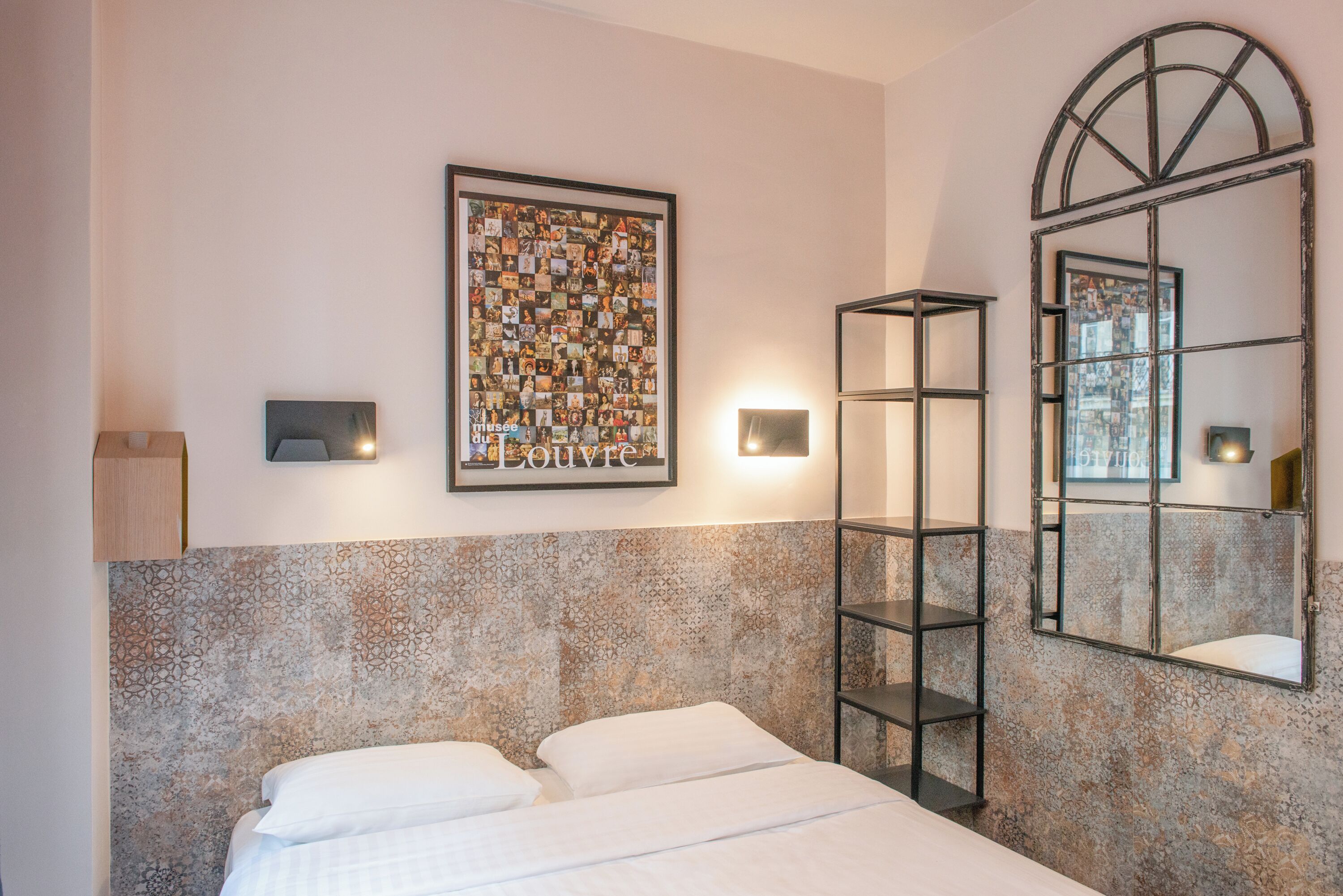 Una habitación de hotel con una cama, un cuadro en la pared, un estante y un espejo.