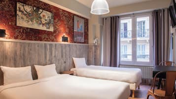 Habitación de hotel con dos camas, cabecero de madera, un ventanal con cortinas, una mesa y una silla.