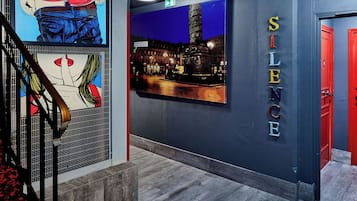 Un interior moderno con una escalera, una zona de bar y una pared con la palabra 'SILENCE' en letras grandes.