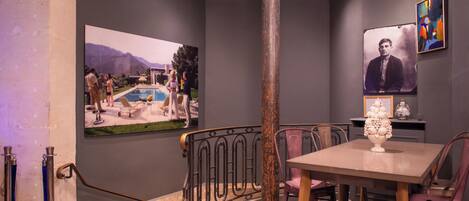 A dining area with a poolside view, a large poster, and a decorative vase on the table.