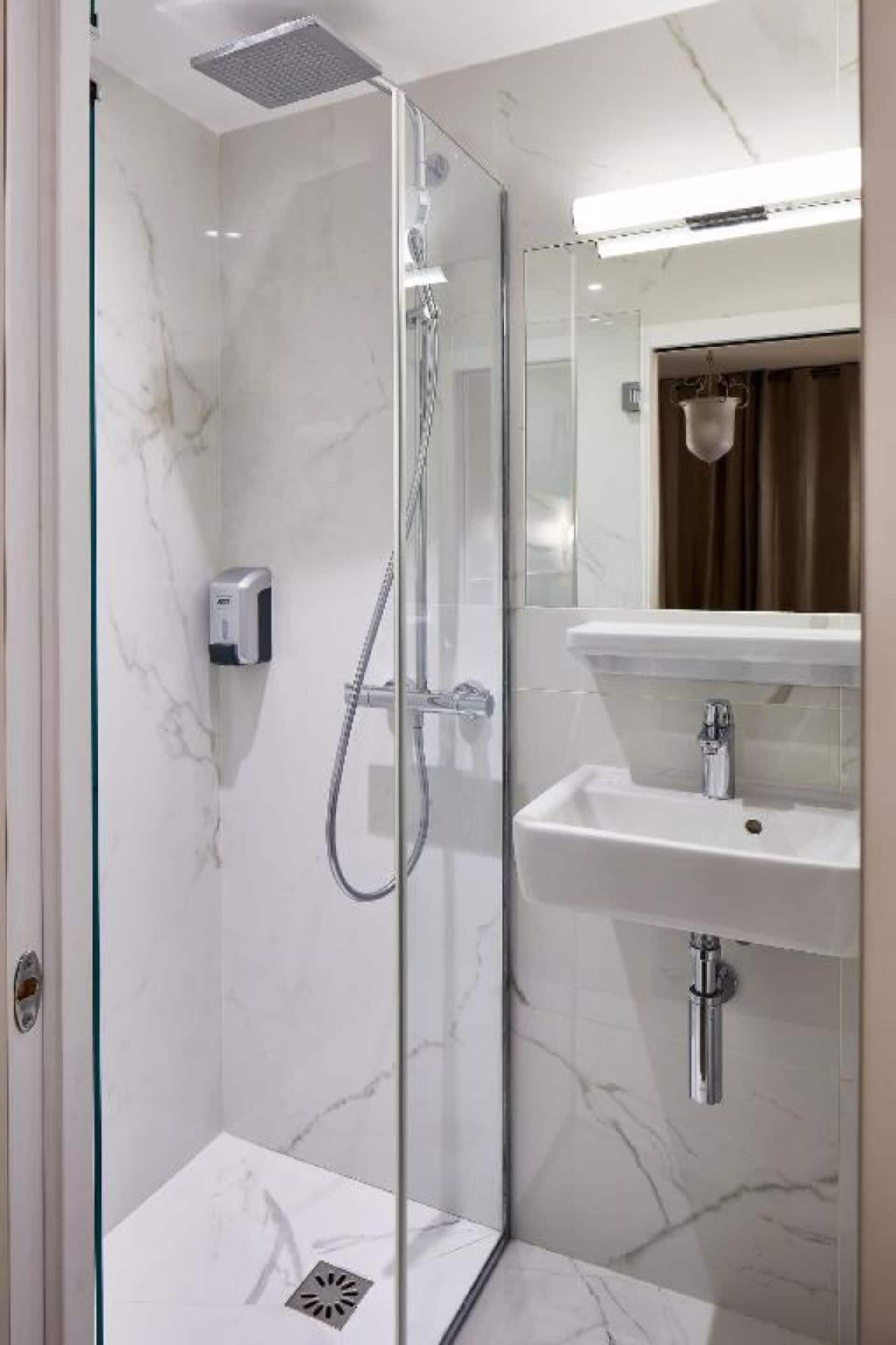 A modern bathroom with a glass-enclosed shower, a white sink, and a mirror above the sink.