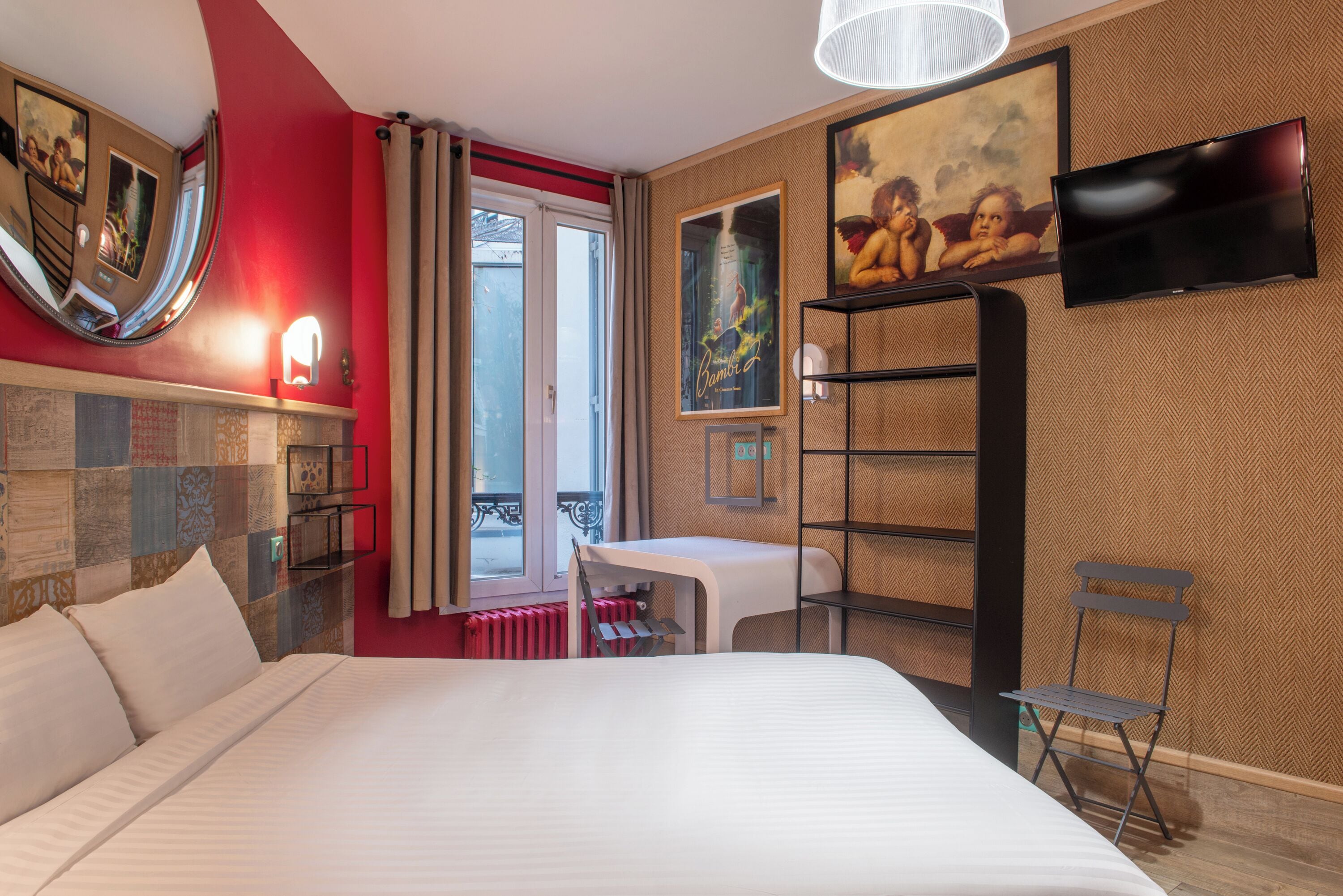 Habitación de hotel con cama, escritorio, silla, televisor y balcón con vistas.