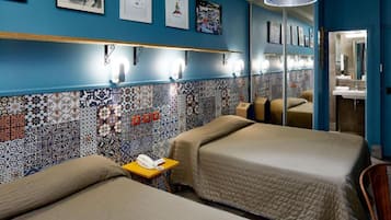 Habitación de hotel con dos camas, una mesita con un teléfono, y una pared decorada con azulejos estampados y fotografías enmarcadas.
