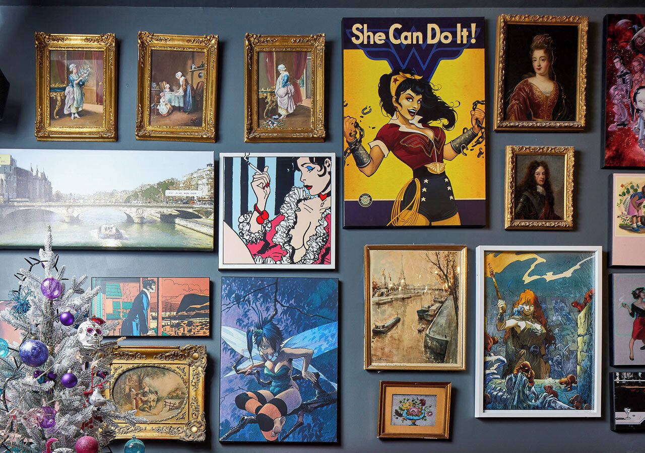 Paredes decoradas com várias obras de arte emolduradas e um pinheiro de Natal enfeitado.