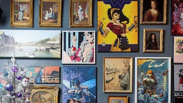 Paredes decoradas com várias obras de arte emolduradas e um pinheiro de Natal enfeitado.