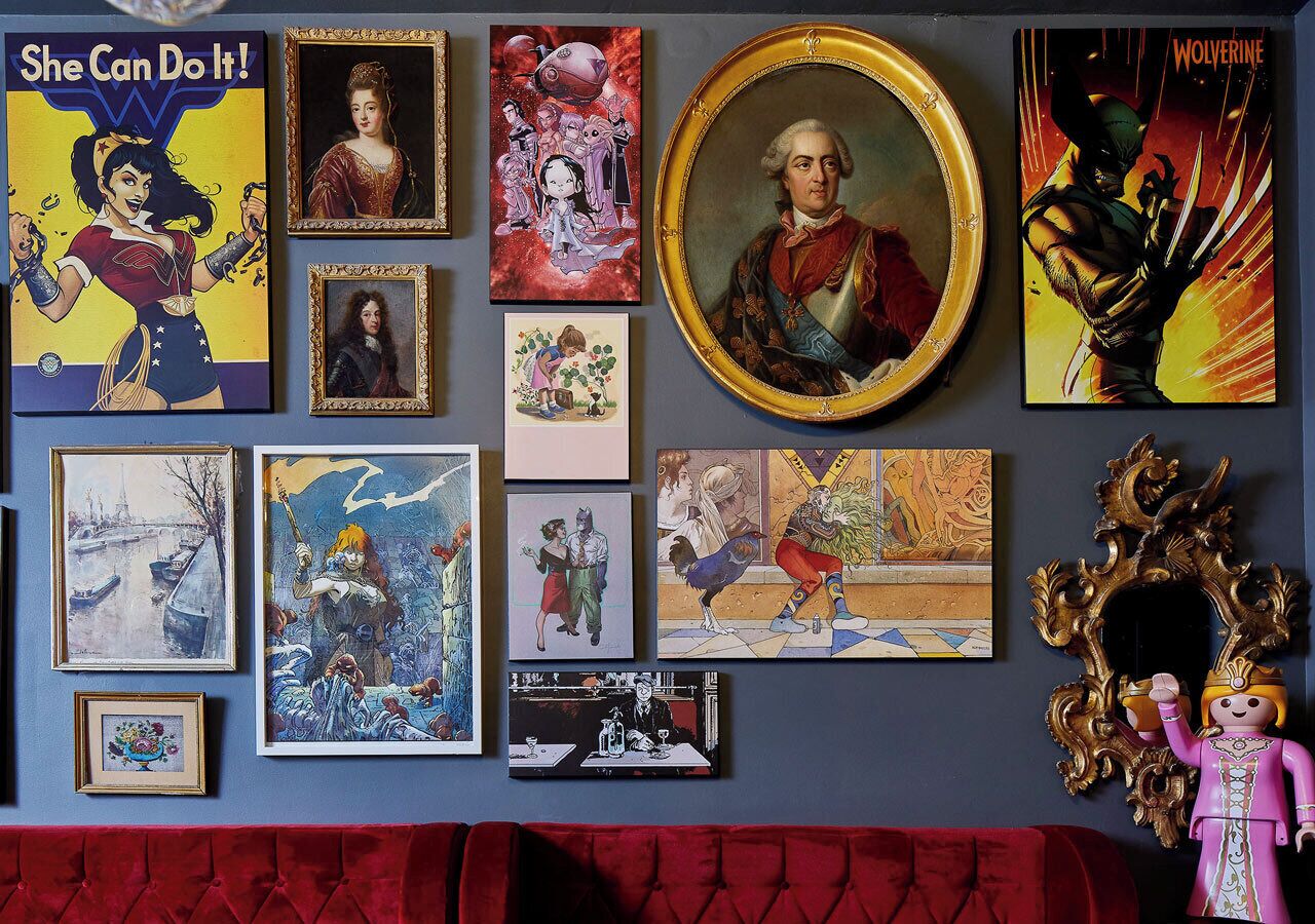 A wall with various framed artworks, including comic book covers and classical paintings.