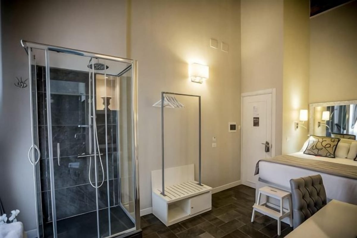A bathroom with a glass-enclosed shower, a vanity with a mirror, and a toilet.