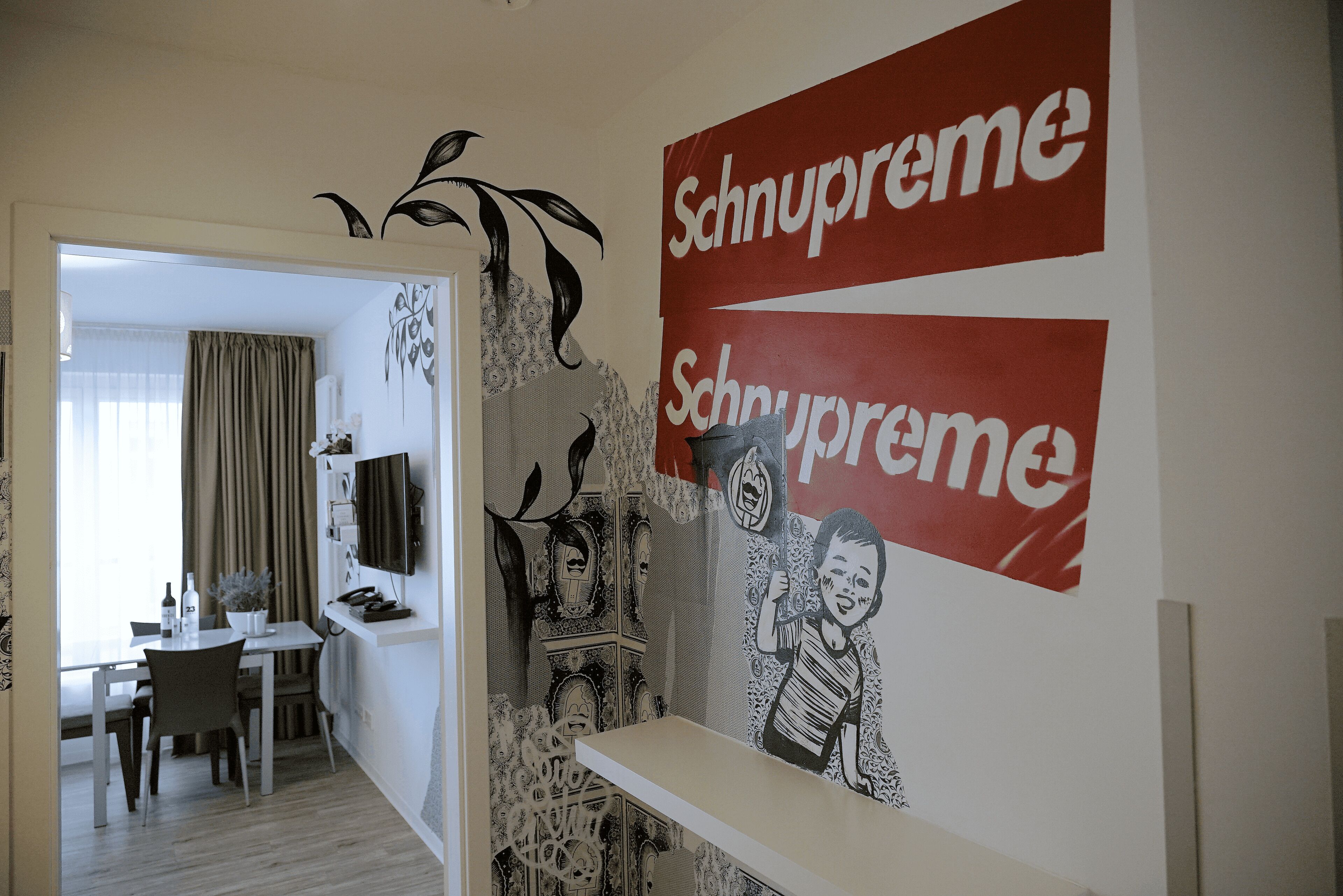 Et værelse med spiseområde, et fjernsyn og en væg med 'Schnupreme'-branding.