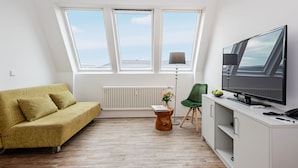 A modern living room with a sofa, a TV, a small table with a lamp, and a radiator. - Apartments Rosenthal Residence (Berlin)