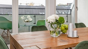 A wooden table with a vase of flowers and candles, a bowl of apples, and a glass of water. - Apartments Rosenthal Residence (Berlin)