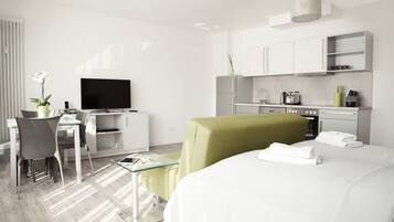 Ein modernes Hotelzimmer mit einem Bett, einem Schreibtisch mit Computer, einem Fernseher und einer Küchenzeile.
