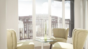 A modern living room with two beige armchairs, a glass coffee table, and a vase with greenery. - Apartments Rosenthal Residence (Berlin)