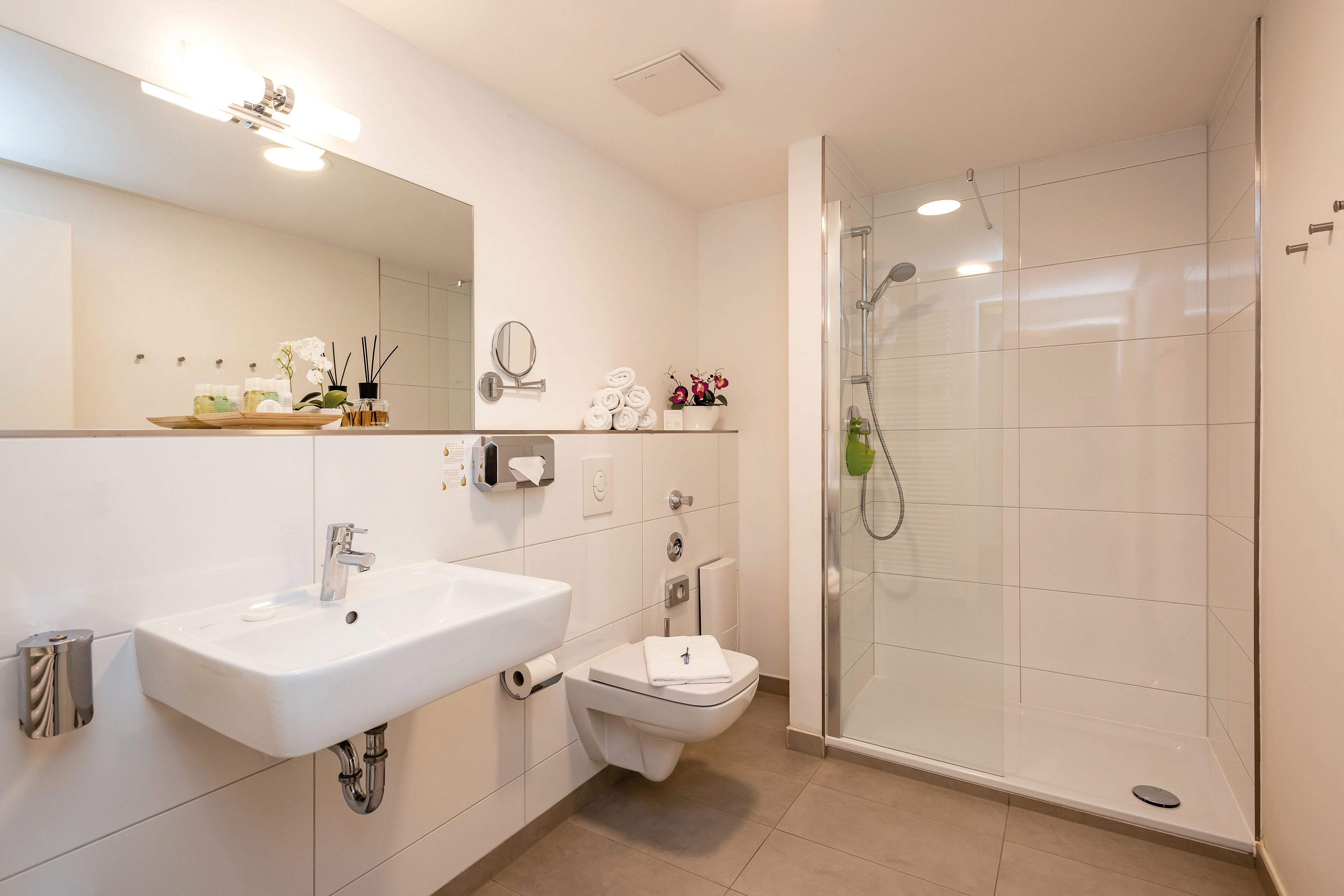 Un baño moderno con lavamanos, inodoro y ducha con cerramiento de vidrio.