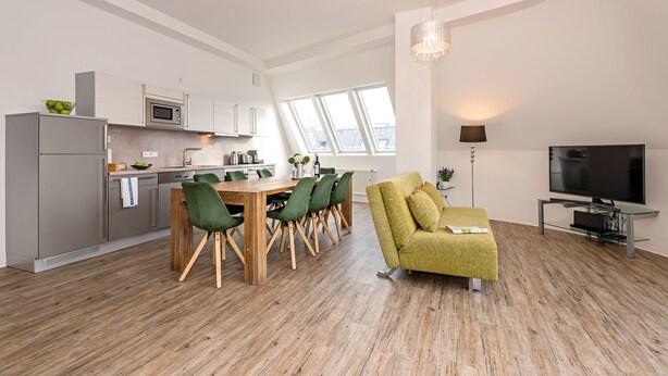 A modern kitchen with a dining area, a sofa, and a TV. - Apartments Rosenthal Residence (Berlin)