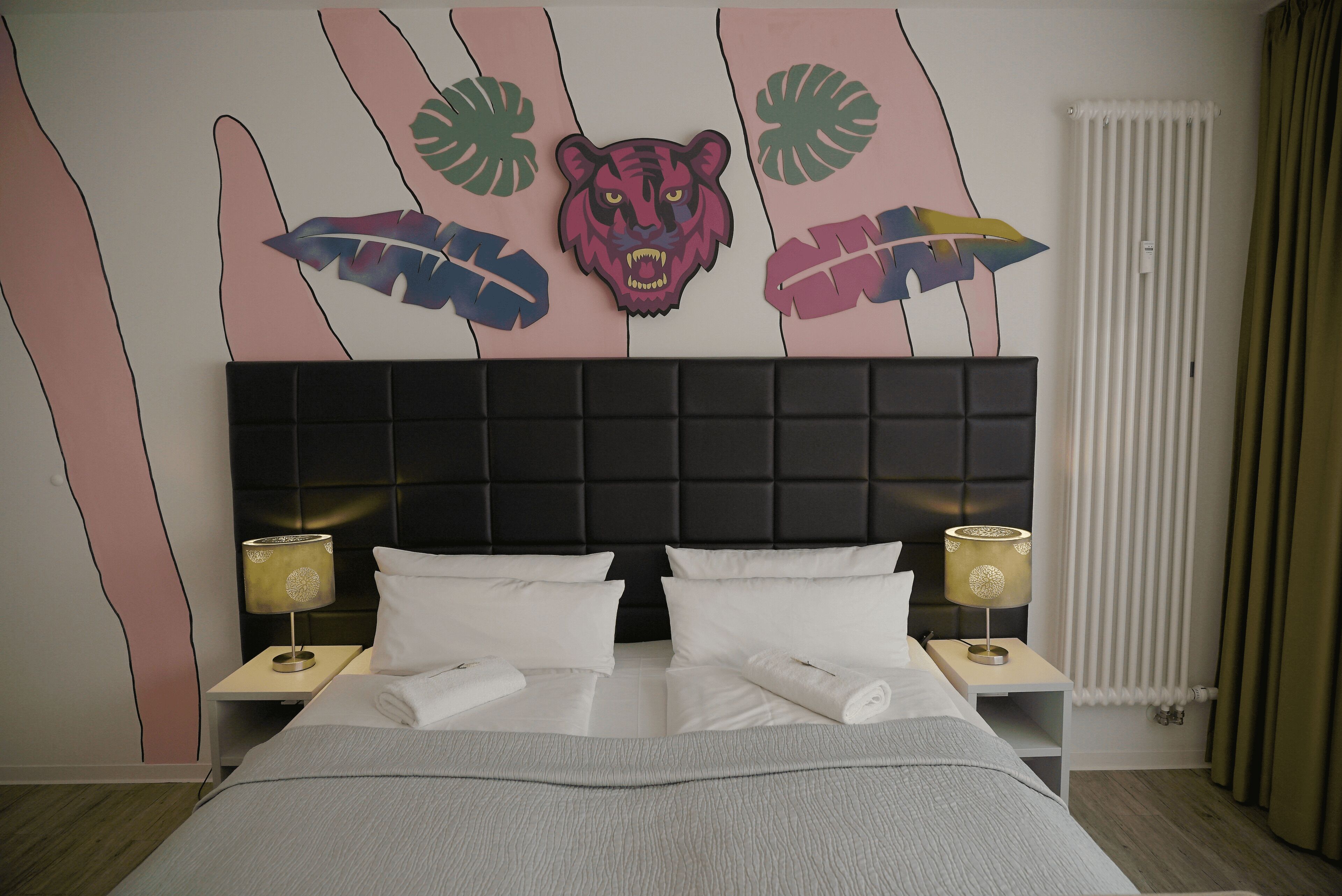 A neatly made bed with white linens, a black headboard, and two bedside lamps.