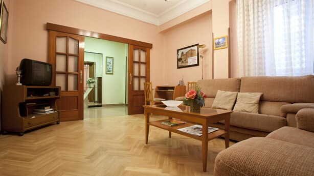 Una sala de estar con un sofá, una mesa de centro, un televisor y una estantería.