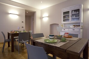 Un comedor con una mesa de madera, sillas y un armario con puertas de vidrio.