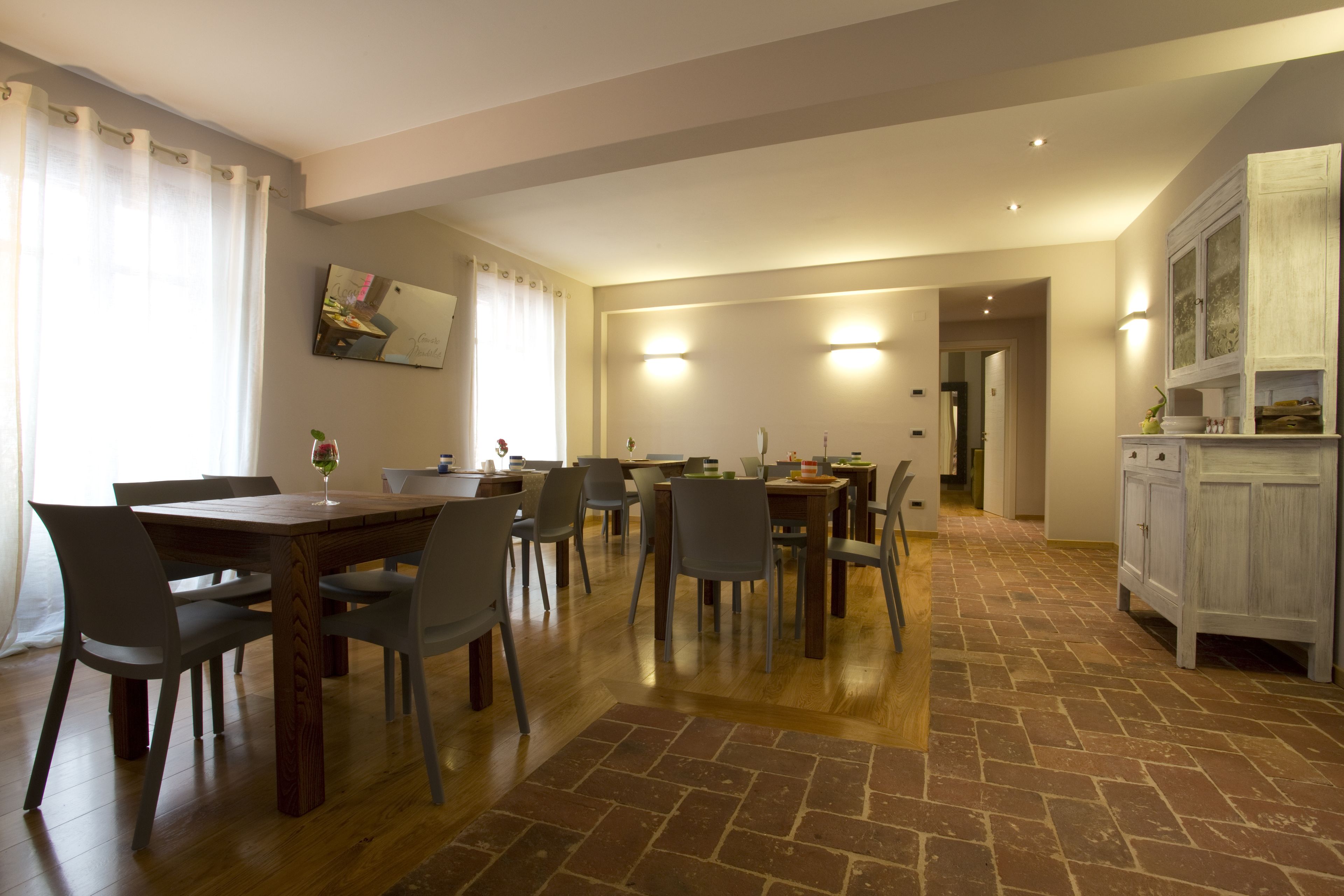 Un comedor amplio con mesa y sillas de madera, una zona de cocina con armarios y un pasillo que lleva a otra habitación.