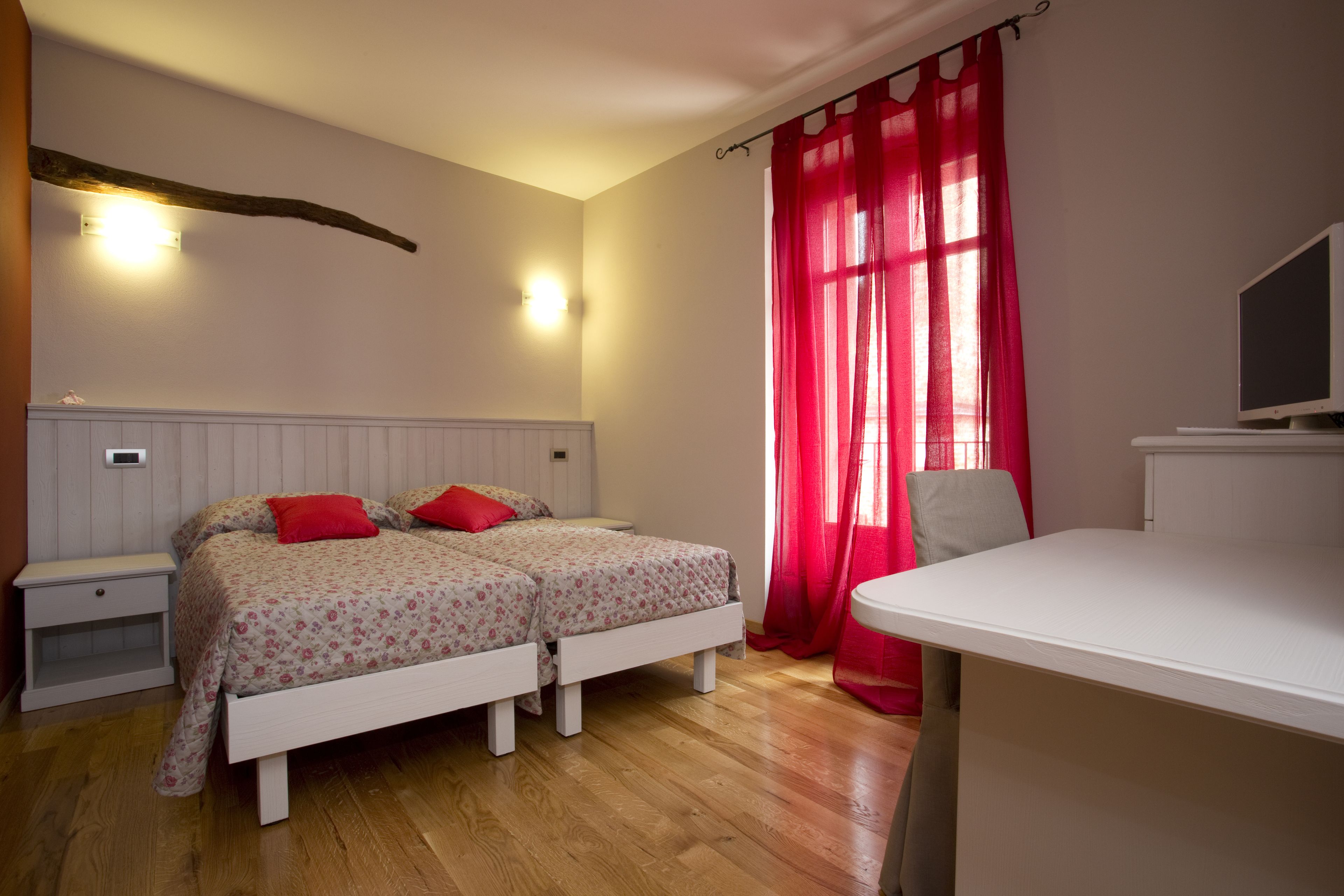 A bedroom with two beds, a desk, and a TV.