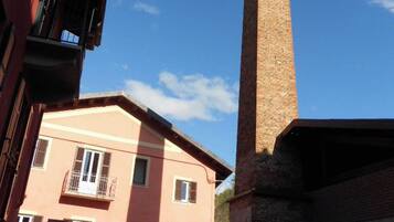 Une haute cheminée en briques, adossée à un bâtiment rose doté d’un balcon.