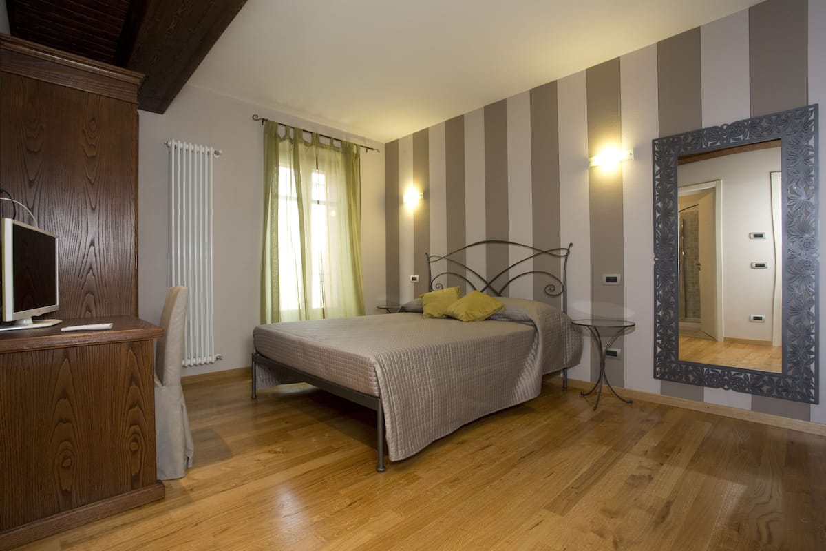 Ein Schlafzimmer mit einem Bett, einer hölzernen Kommode, einem Spiegel und einem Heizkörper.