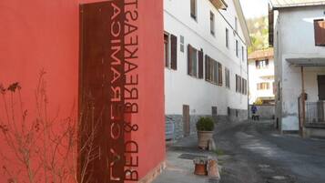 A narrow street with a building featuring a red door and a sign that reads "BED & BATHES."