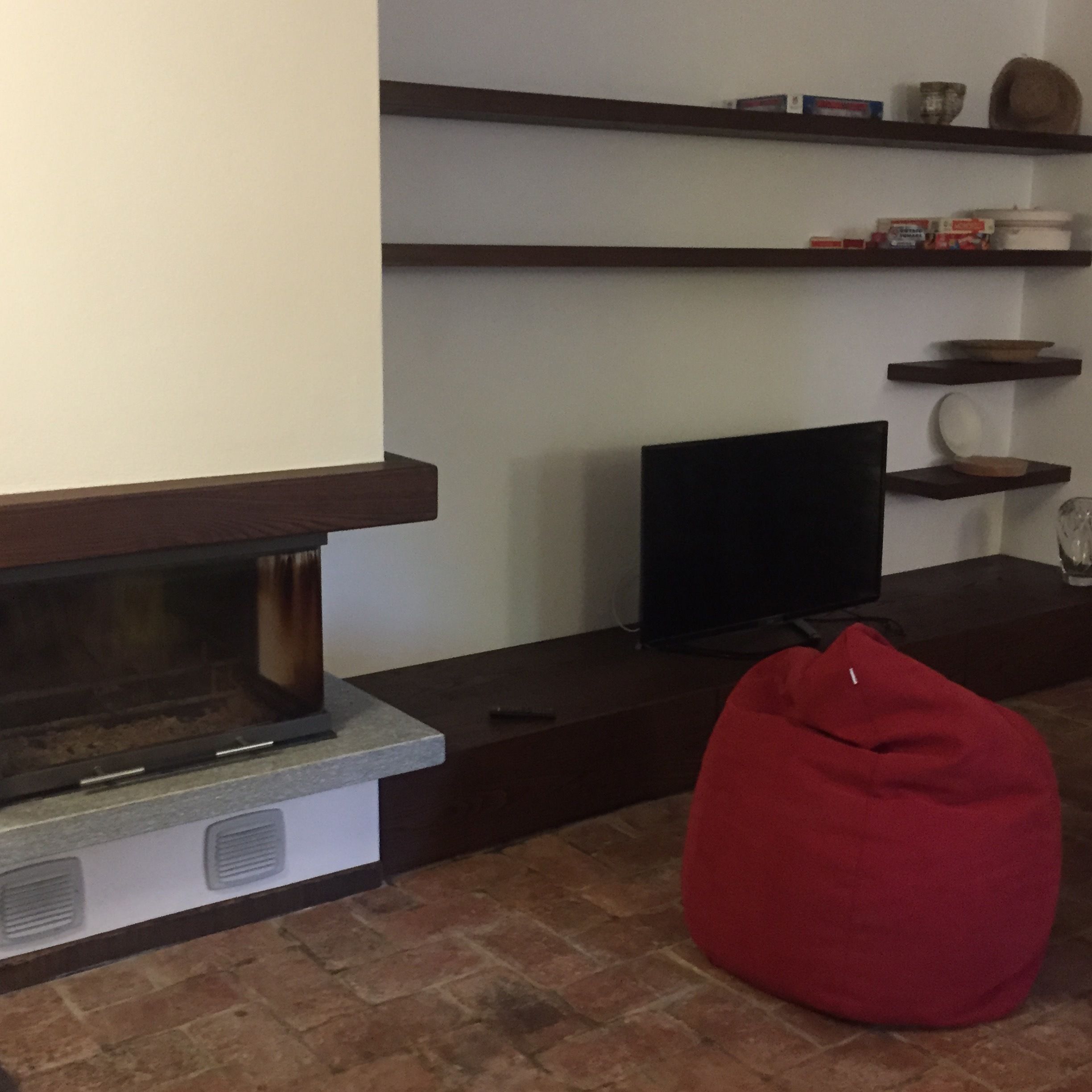 A living room with a fireplace, a television, and a red bean bag chair.