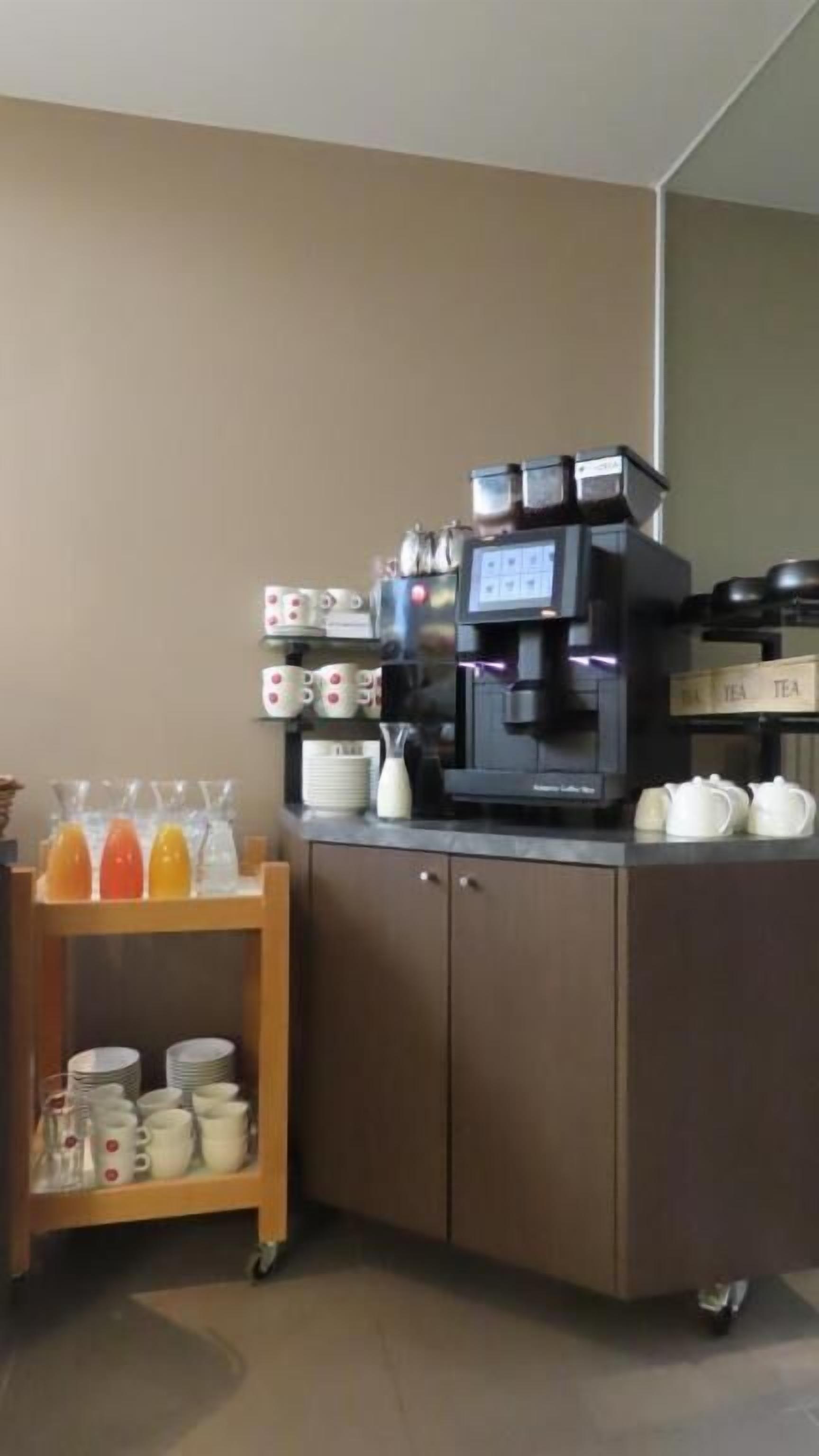 Una estación de café con una máquina de café, tazas y una estación de té.
