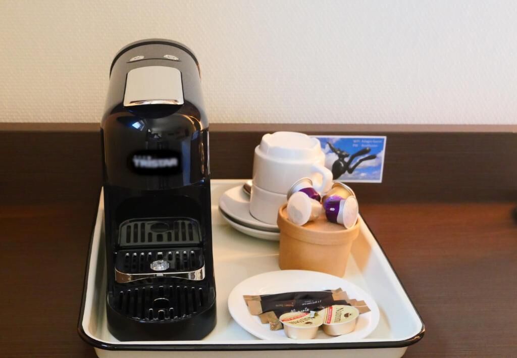 A tray with a coffee maker, a cup of coffee, a plate with chocolate bars, and a cup with a decorative item.