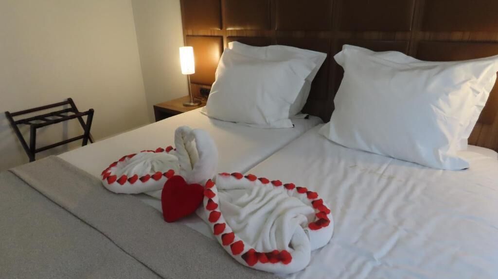 A hotel room with a neatly made bed, a bedside lamp, and a chair.