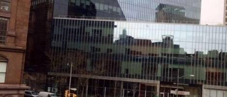 A modern building with a glass facade and a classic stone structure to the left.