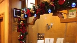 A wooden reception desk with a glass partition, a potted plant, and Christmas decorations. - St Marks Hotel (New York)