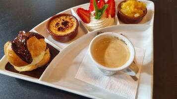 Un plateau avec une crêpe, une crème dessert, une salade de fruits et une tasse de café.