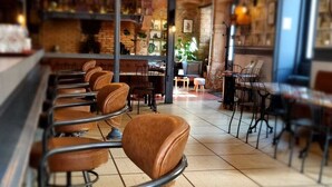 Een bar met leren barstoelen, een betegelde vloer en hangende lampen.