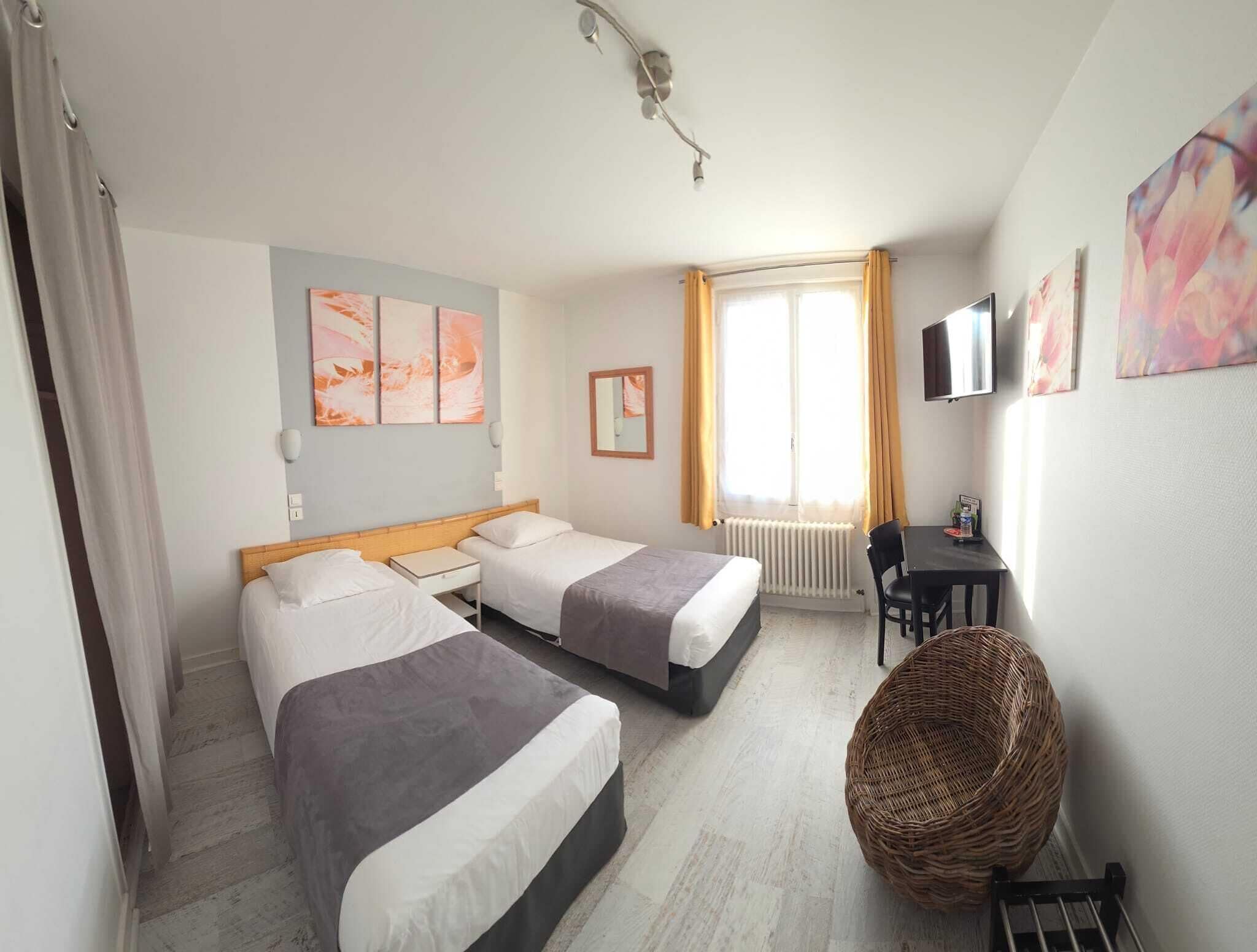 Een hotelkamer met twee bedden, een bureau, een stoel, een televisie en kunstwerken aan de muren.