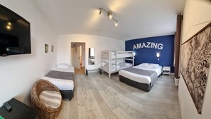 Hotelkamer met twee bedden, een televisie, een muur waarop 'AMAZING' staat en een groot kunstwerk aan de rechterkant.