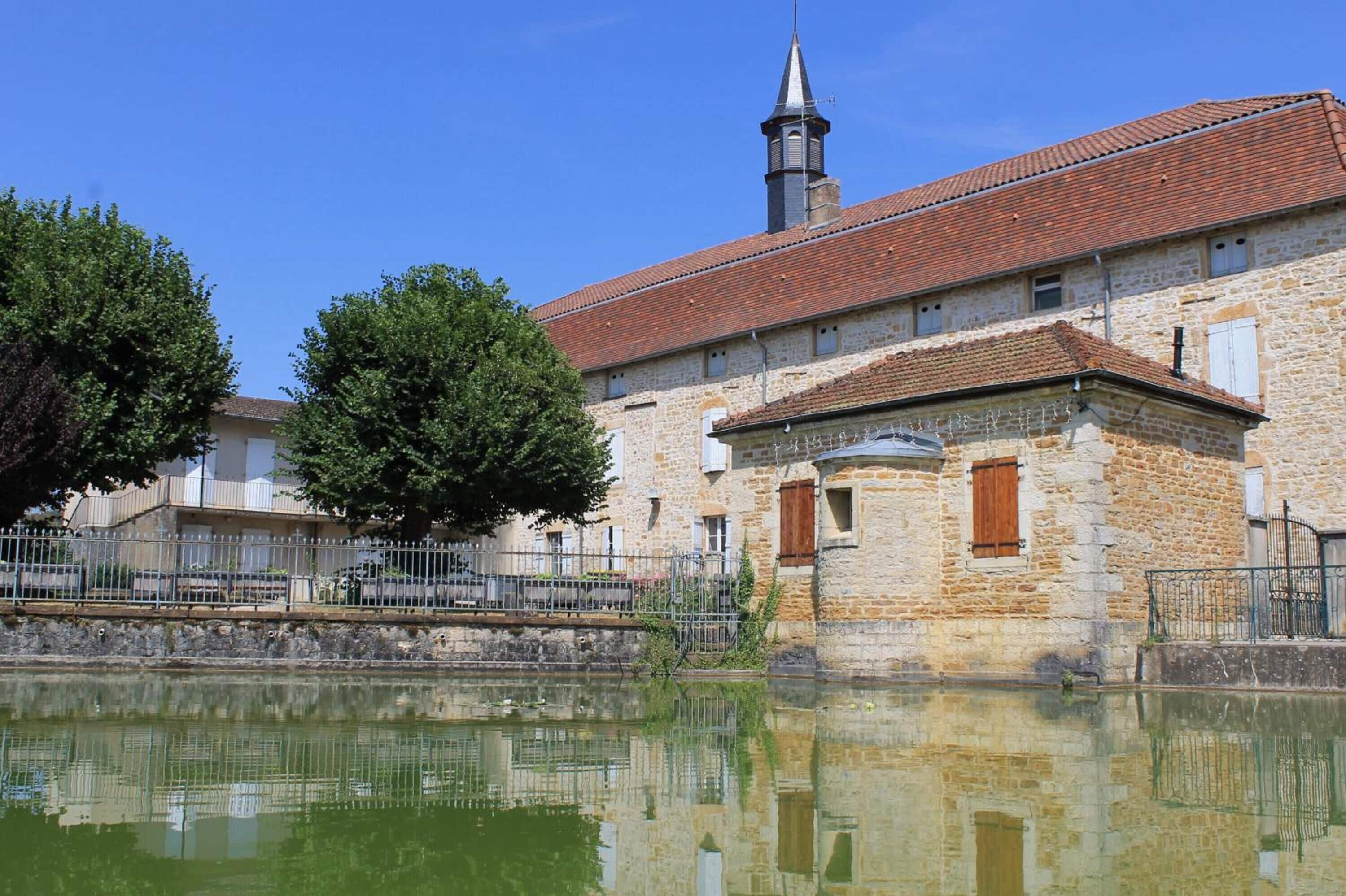A stone building with a tiled roof and a church steeple.