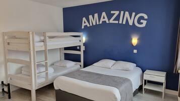 Une chambre avec un lit superposé, un lit simple, une table de chevet et un mur sur lequel est écrit le mot « INCROYABLE » en grandes lettres.