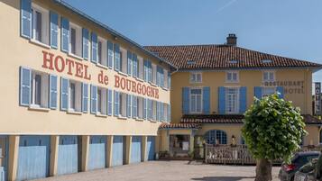 Un hotel con un cartel que dice "HOTEL de BOURGOGNE" y un letrero de restaurante en el edificio contiguo.