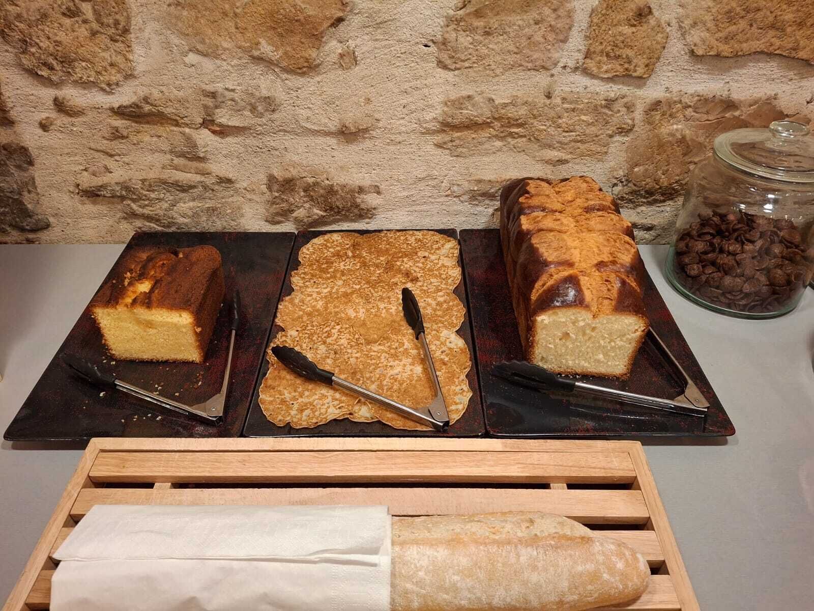 Three loaves of bread on a tray with a knife and a wooden bread box.