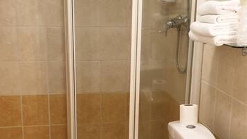A bathroom with a glass-enclosed shower, a toilet, and a sink.