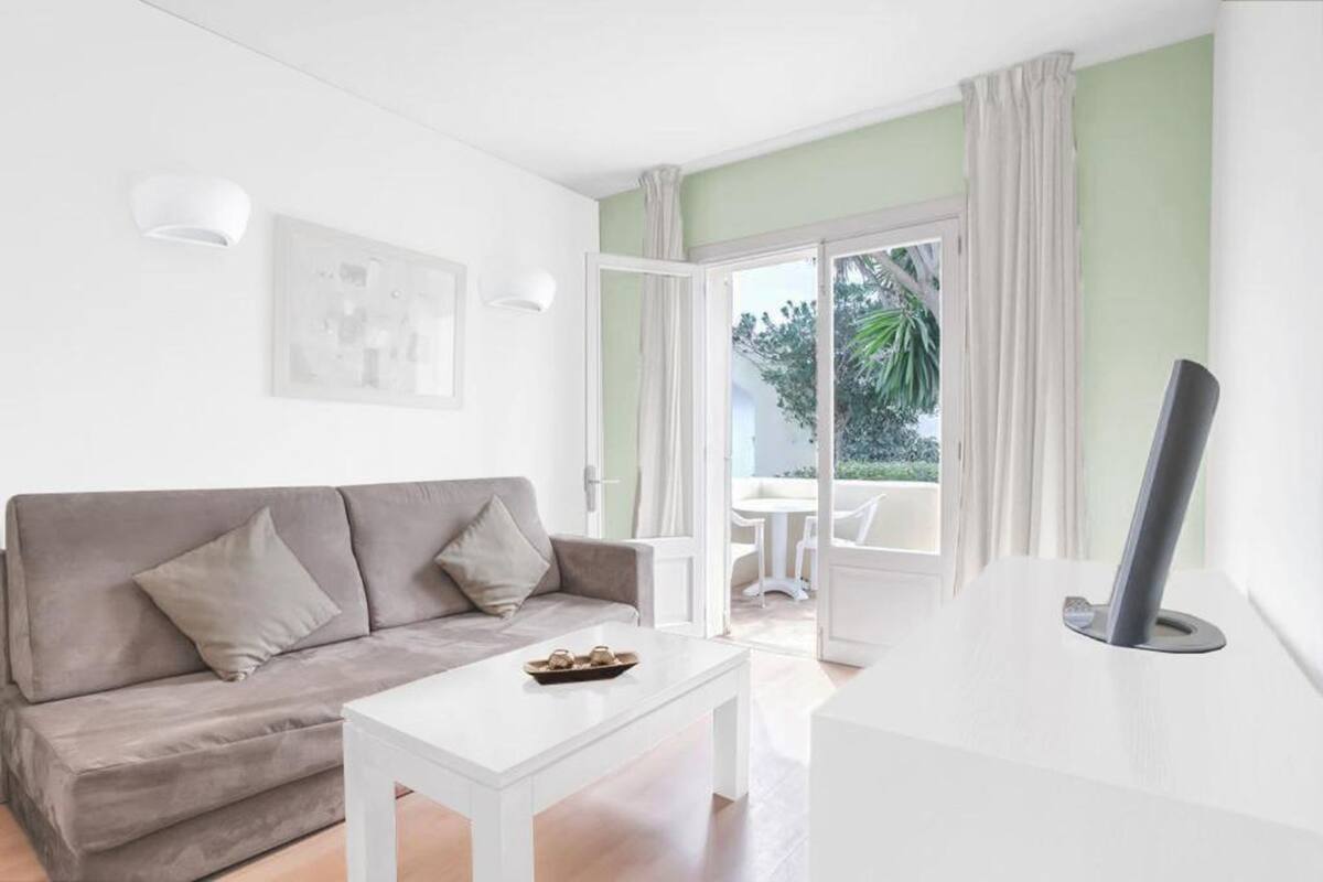 A modern living room with a grey sofa, a white coffee table, and a flat-screen TV.