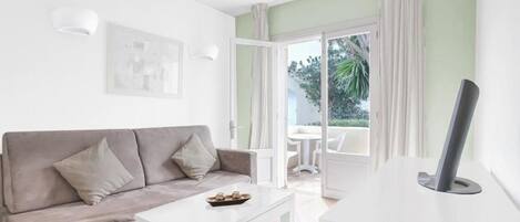 A modern living room with a grey sofa, a white coffee table, and a flat-screen TV.