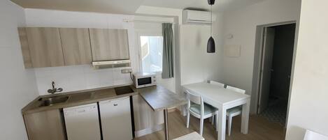 Una cocina moderna con lavavajillas, microondas y comedor con mesa y sillas.