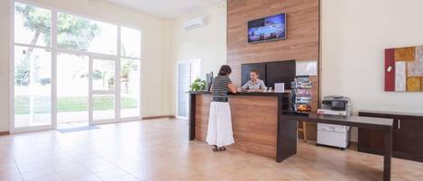 Un área de recepción con un mostrador de madera, un televisor de pantalla plana y un ventanal que ofrece vistas al exterior.