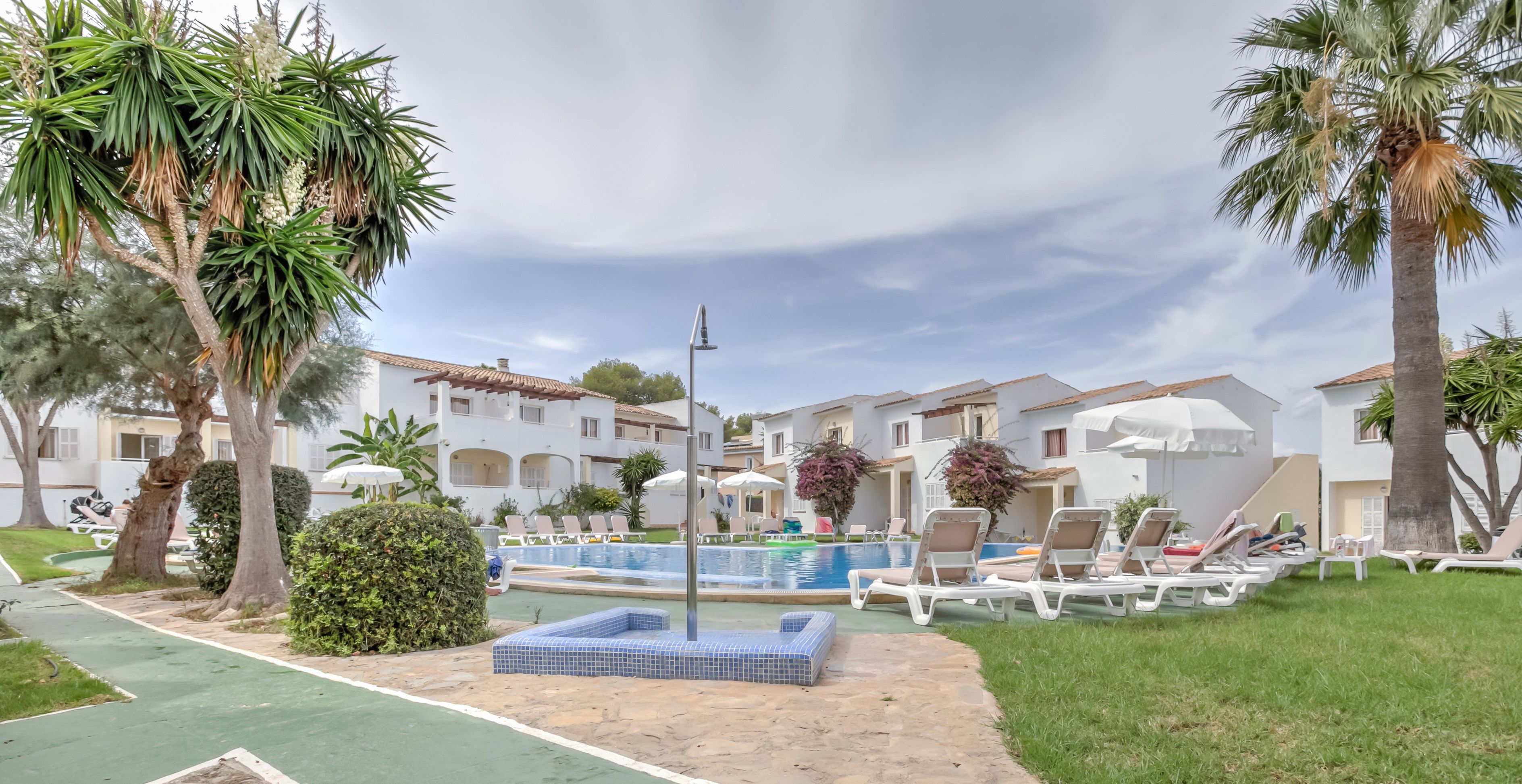 Una piscina al aire libre, sombrillas, tumbonas